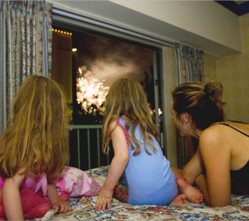 mama in hčeri gledajo ognjemet skozi okno
