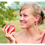 nasmejana ženska drži v roki jabolko