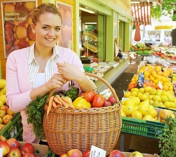ženska na tržnici s košaro polno zelenjave